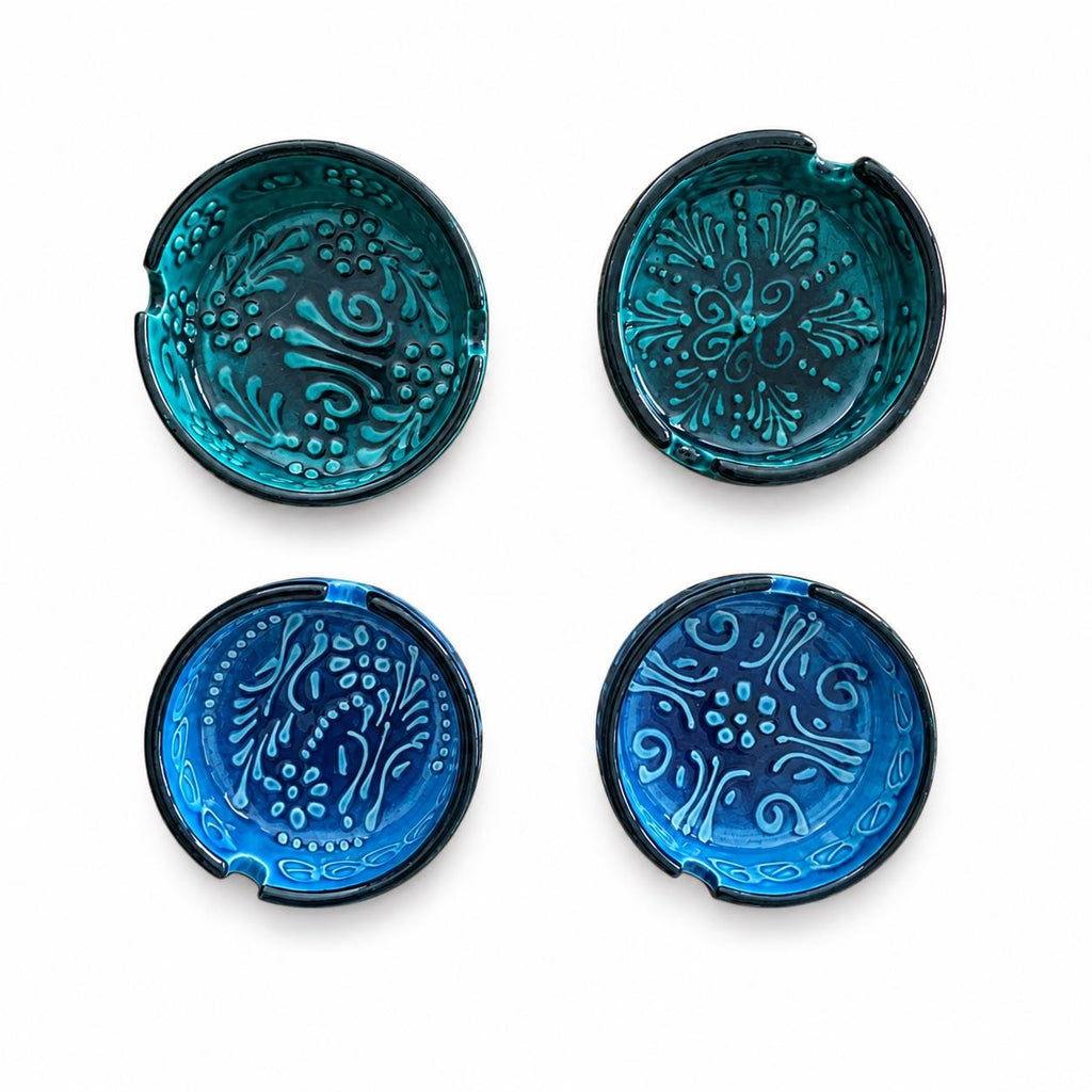 Four embossed ceramic ashtrays in teal and blue glazes