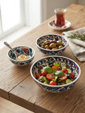 Three hand-painted ceramic serving bowls filled with salad olives and dip